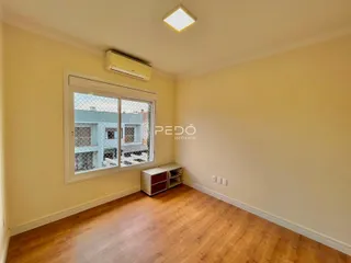 Ambiente interno de uma sala com piso de madeira e janela.