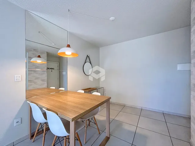 Foto de um ambiente interno com mesa de jantar de madeira e cadeiras brancas.