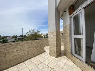 Vista da varanda com piso de cerâmica e muro de alvenaria.