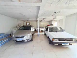 Foto de um espaço amplo com dois veículos estacionados em um ambiente com teto de vigas.