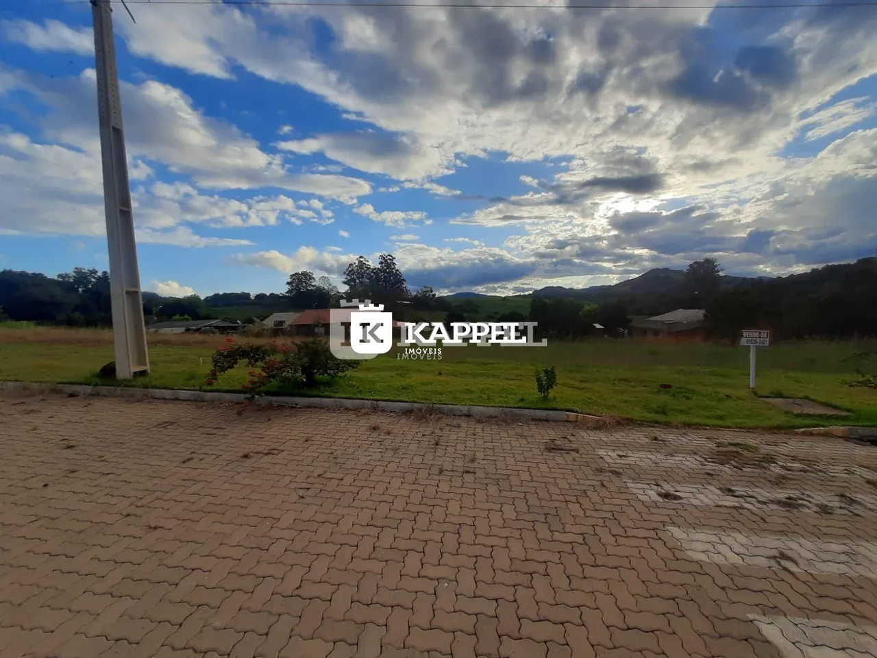 Vista de campo aberto com colinas ao fundo sob um céu nublado.