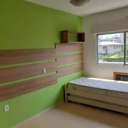 Sala de estar com parede verde e painel de madeira.