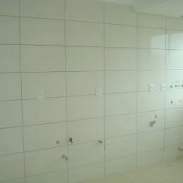 Parede interna com revestimento de azulejos brancos na propriedade.