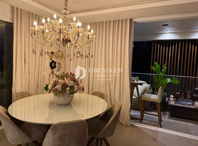 Uma sala de jantar com mesa redonda e lustre dourado.