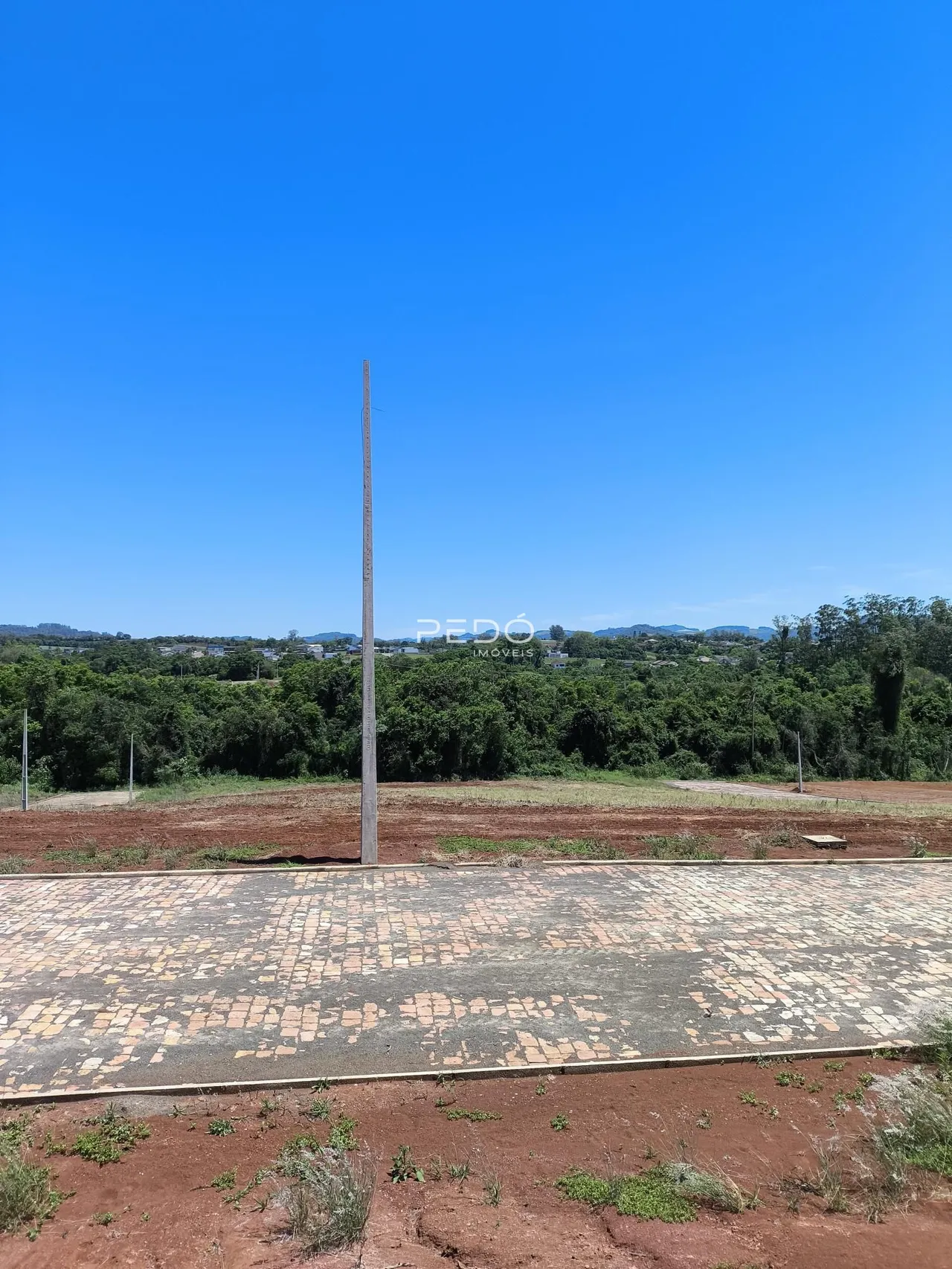 Vista aérea de uma área de terra com um poste no meio, cercada por vegetação.