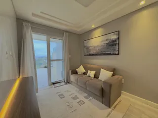 Sala de estar com sofá e grande janela com vista externa.