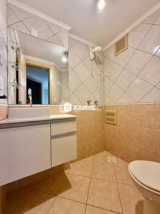 Foto de um banheiro com revestimento de azulejos claros e bancada branca.