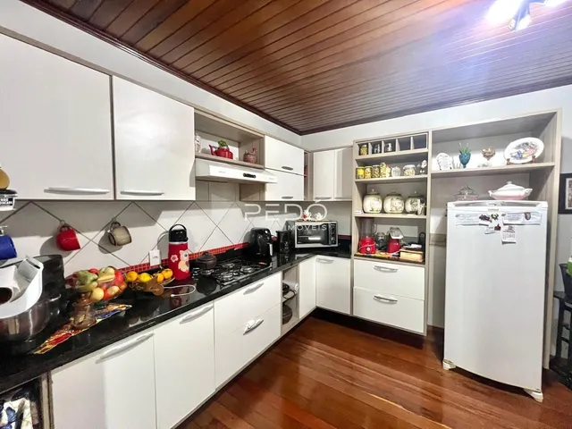 A cozinha apresenta armários brancos e bancadas escuras com piso de madeira.