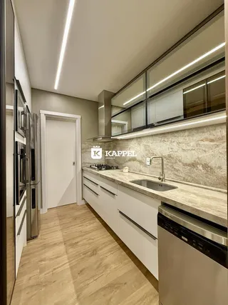 Cozinha moderna com armários brancos e bancadas de mármore clara.