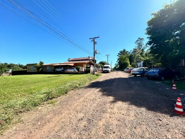 Vista externa de uma propriedade com gramado e estrada de terra.