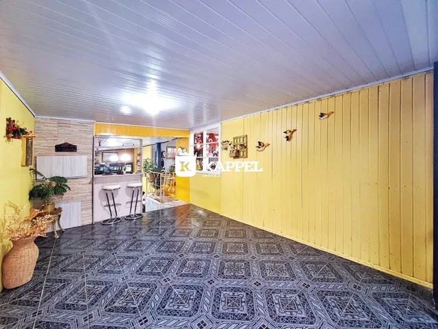 Ambiente interno com piso de ladrilhos escuros e paredes amarelas em uma residência.