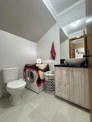 Foto de um banheiro mostrando um vaso sanitário e uma máquina de lavar roupa.