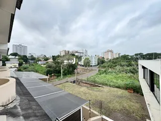 Vista externa de uma área verde com residências ao fundo.