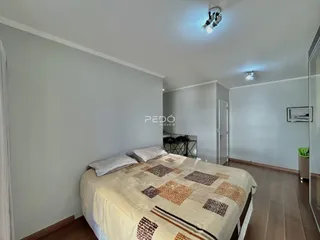 Quarto com cama e piso de madeira clara.