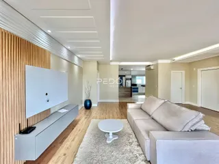 Sala de estar moderna com piso de madeira clara e sofá bege.