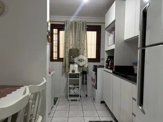 Vista interna da cozinha com armários brancos e piso de cerâmica.