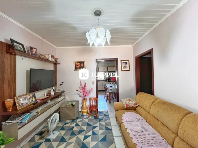 Sala de estar com sofá e televisão em um ambiente claro.