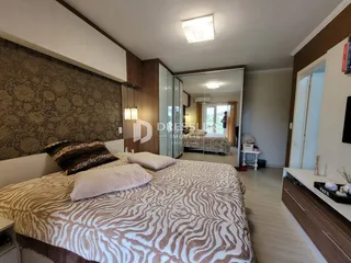 Quarto com cama grande e parede decorada em tons terrosos.
