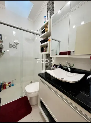 Banheiro moderno com bancada preta e revestimento branco.