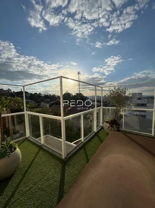Vista da varanda com piso gramado e grade de vidro.
