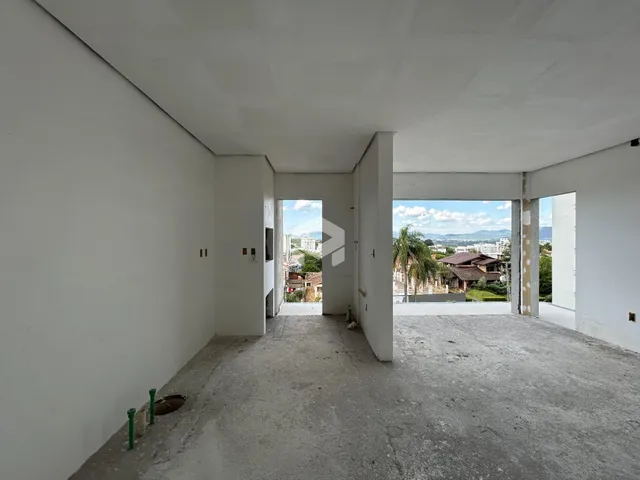 Vista de um corredor interno com paredes brancas e piso de concreto.