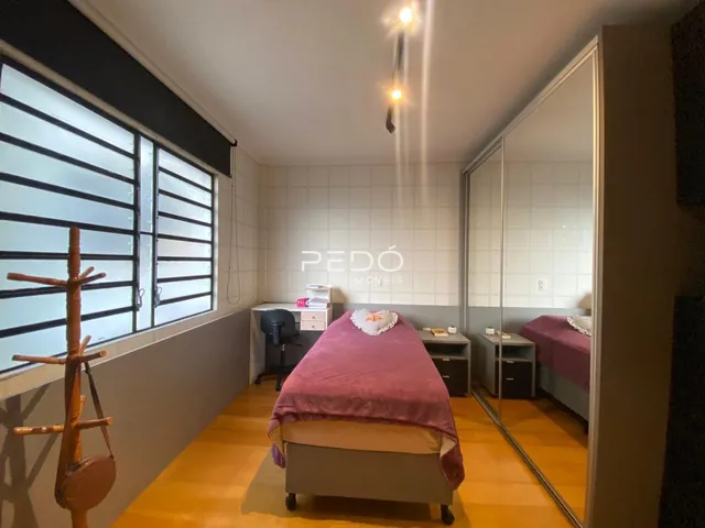 Quarto com piso de madeira e janela com persianas.