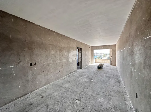 Corredor interno com paredes de concreto aparente e piso de concreto.