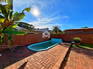 Vista externa de uma piscina e pátio de tijolos em uma propriedade no Brasil.