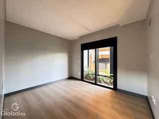 Foto do interior de uma sala com piso de madeira e porta de vidro.