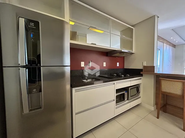 Cozinha moderna com armários brancos e bancadas escuras.