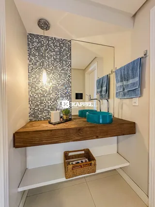 Banheiro com bancada de madeira e revestimento de azulejos escuros.