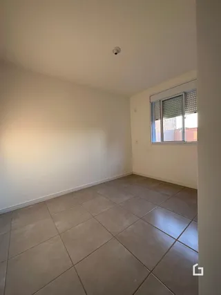 Vista interna de uma sala com piso de cerâmica clara e parede branca.