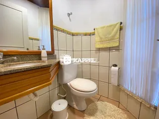 Banheiro com bancada de madeira e revestimento de azulejos brancos.