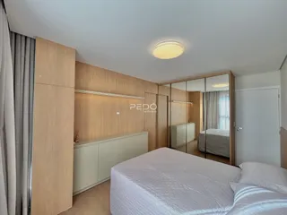 Quarto com armários em madeira e cama de casal.
