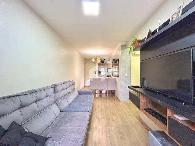Uma sala de estar com sofá e piso de madeira clara.