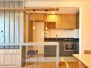 Vista interna de uma cozinha moderna com armários de madeira e bancada escura.
