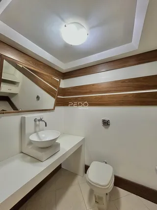 Interior de um banheiro com revestimento de madeira e bancada branca.