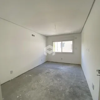 Ambiente interno de uma sala com piso de concreto cru e paredes brancas.