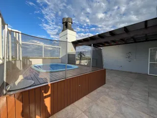 Foto da área externa com piscina e deck de madeira em uma residência.