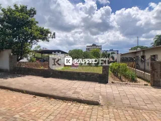 Fachada externa da propriedade mostrando um muro de tijolos e área pavimentada.