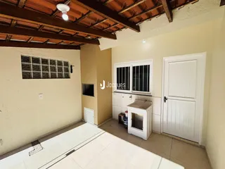 Ambiente interno de uma sala com piso de cerâmica e estrutura de madeira exposta.