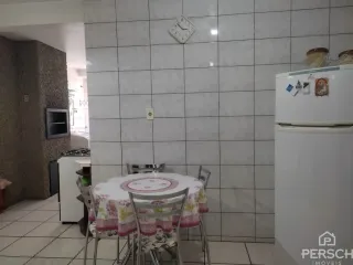 Uma mesa posta com toalha branca e detalhes em rosa está visível na sala.