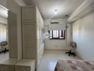 Quarto com armários brancos e piso claro.