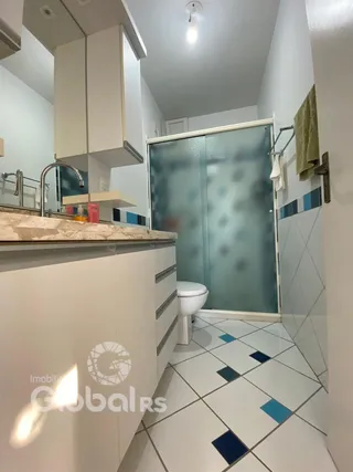 Foto de um banheiro com piso de azulejos brancos e box de vidro.