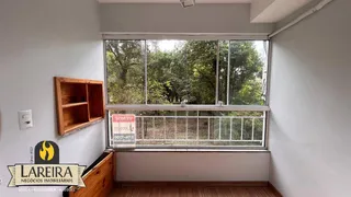 Uma sala interna com uma grande janela que oferece vista para a vegetação externa.