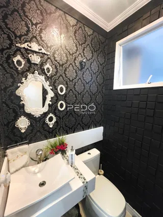 Detalhe de um banheiro com revestimento de parede escuro e louças brancas.