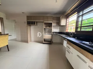 Vista interna de uma cozinha com armários de madeira e piso de cerâmica.