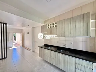 Cozinha moderna com armários em tom de madeira clara e bancada preta.