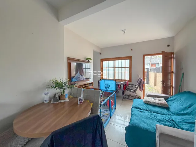 Ambiente interno de uma sala com cama e mesa de madeira em Lajeado.