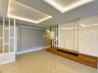 Ambiente interno de uma sala de estar moderna com piso claro e armários brancos.